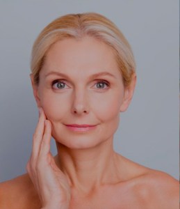 older smiling woman touching her face