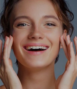 woman touching her face with both hands and smiling