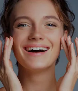 woman touching her face with both hands and smiling